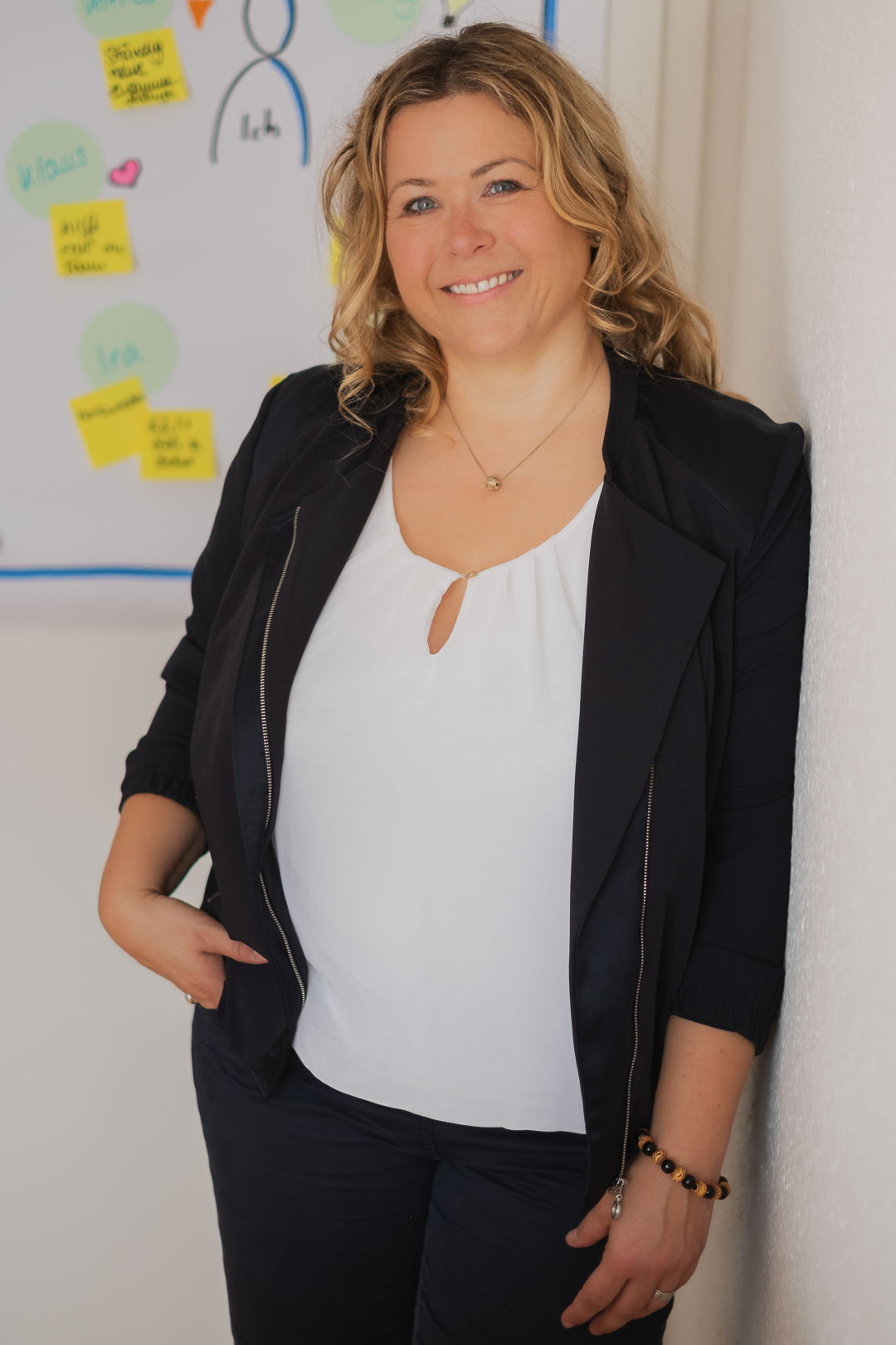 Portrait von Karrierecoach Cornelia Schowald an eine Wand gelehnt